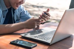 Close Up Asian Young businessman work at outdoor with laptop. Concept of remote and freelance work. Young successful man wearing casual blue cloth.