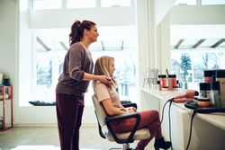 Side view of hairdresser showing client new haircut though reflection of mirror