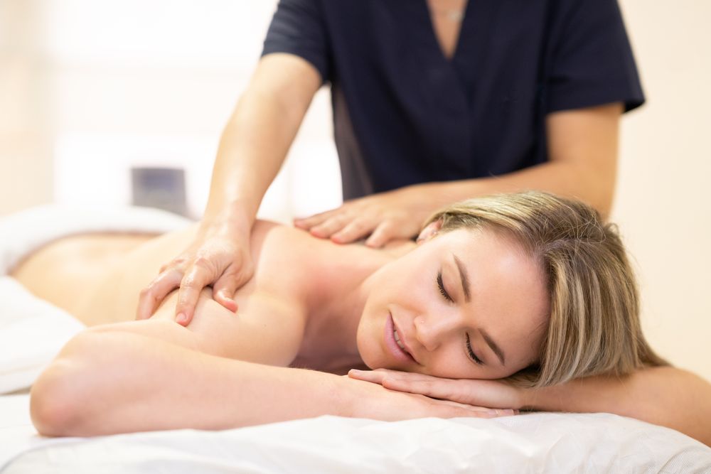 Blonde female having shoulders massaged on the table
