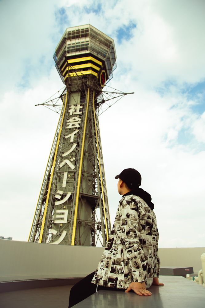 Man wearing casual outwear sitting on balustrade near Shanghai tower in China