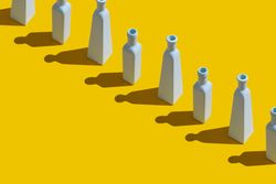 Single row of painted glass bottles on yellow background