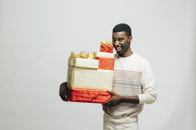 Happy Black man holding pile of wrapped presents