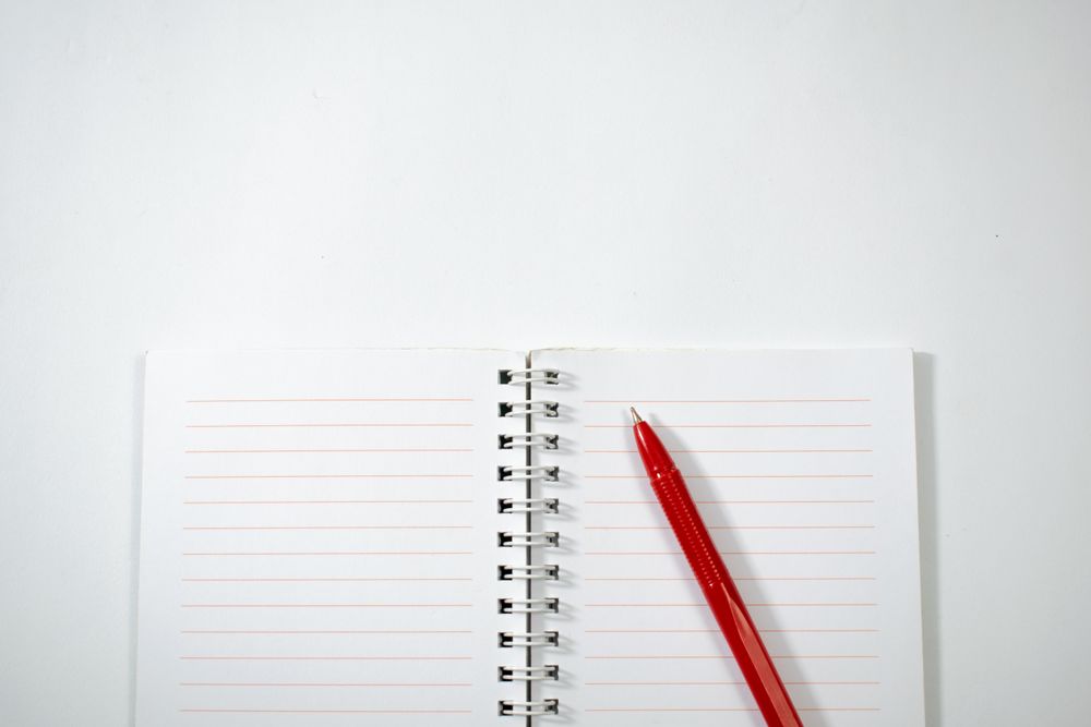 Open notebook and red pen isolated on plain background