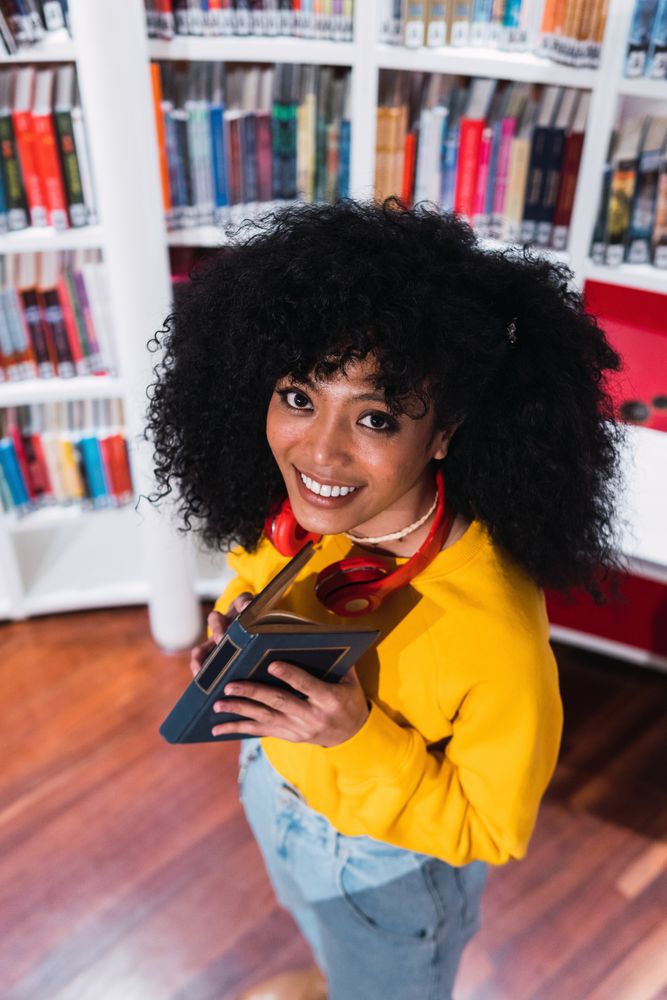 Content female student reading textbook in library