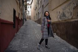 Joyful Asian resting female hiking on old rocked narrow street