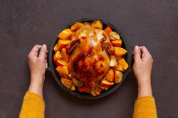 Person placing chicken in pot on table