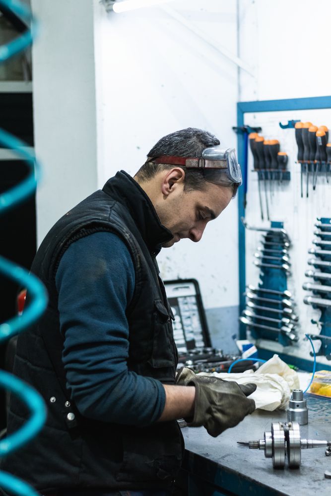 Professional mechanic using spanner while assembling vehicle engine details at workbench