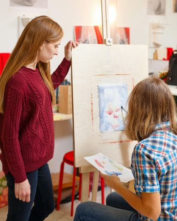 Female art teacher observes the student