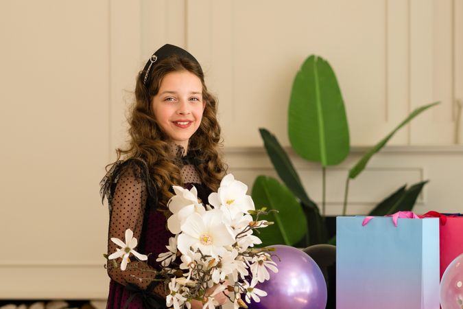 Girl holding flowers and smiling at birthday celebration.