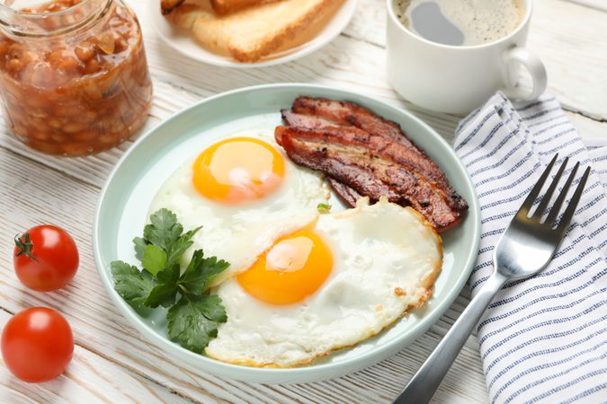 Two fried eggs and bacon sunny side up on plate