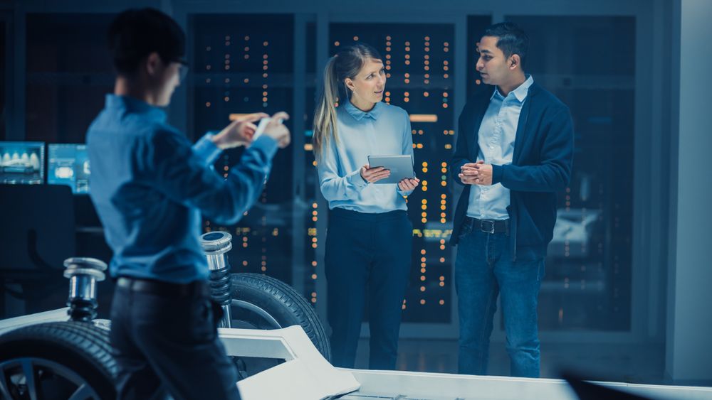 Automotive Design Engineer and Scientist with Tablet Discuss the Electric Car Chassis Prototype.