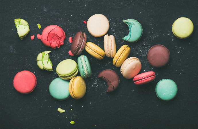 Assortment of multi-colored macaron pastries against a dark background