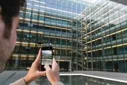 Man shooting building facade with smartphone in downtown