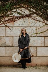 Pensive woman with lyre against brick wall