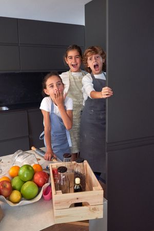 Terrified girls and boy against table in kitchen
