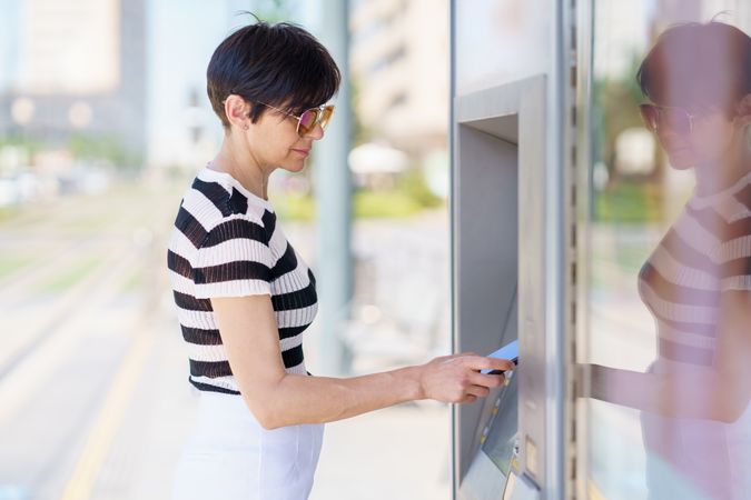 Woman using ATM on sunny day