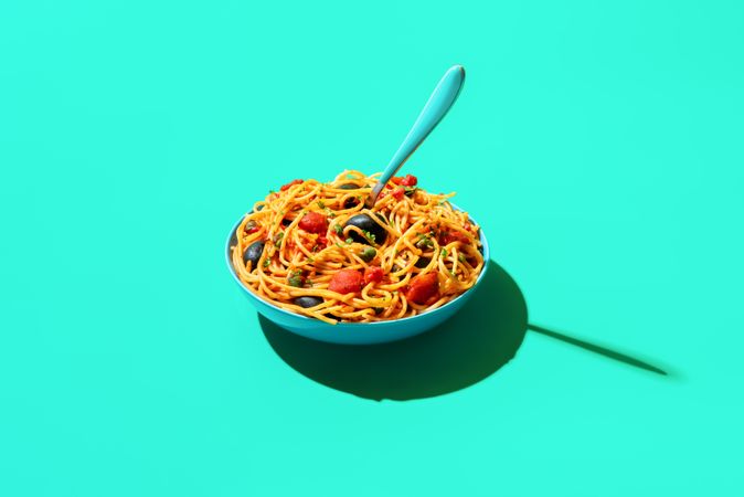 Pasta puttanesca bowl isolated on a green background