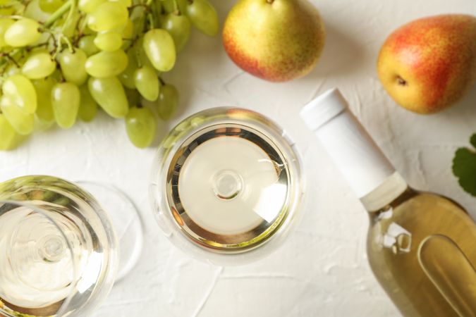 Pears, grape, bottle and glass with wine on plain background, top view