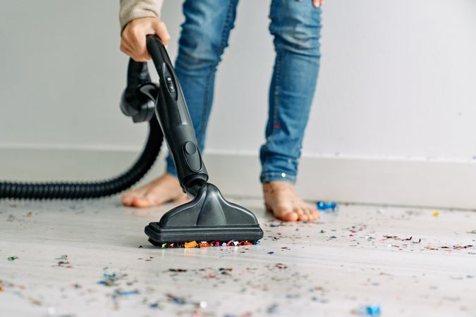 Child collecting festive confetti with vacuum cleaner