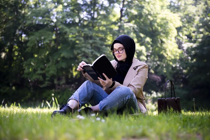 Calm woman in head scarf reading in the park