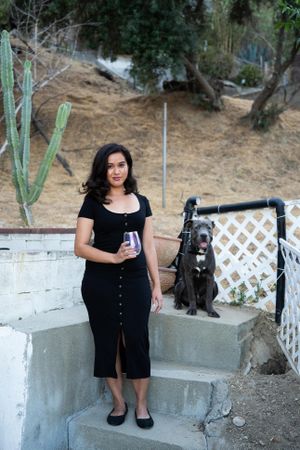 Portrait of woman and her dog looking at camera outside with hillside and cactus behind them