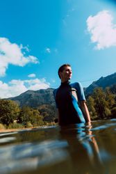 Young female in wetsuit standing in water