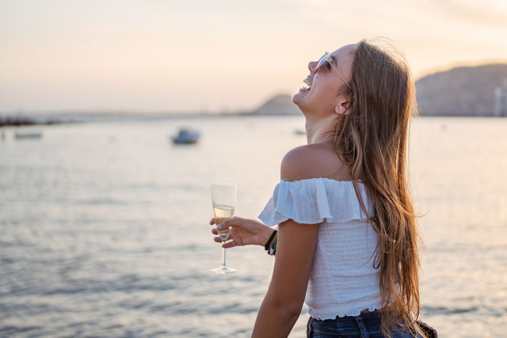 Young woman enjoying wine near sea