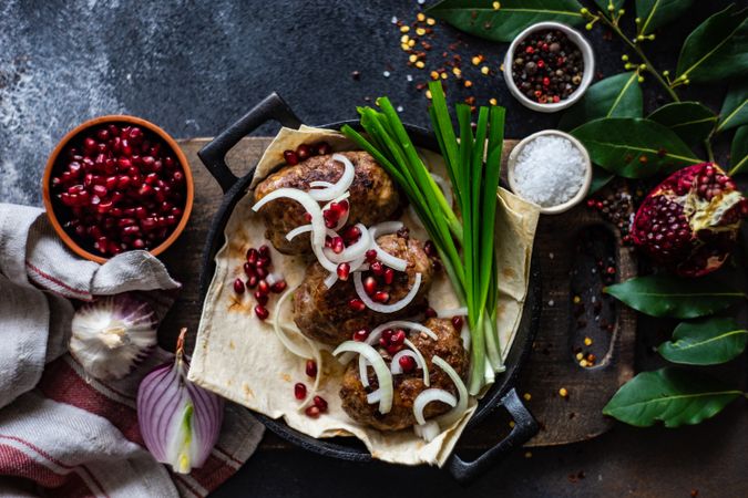Top view of Georgian plate of abkhazura meat cutlets with pomegranate seeds, bay leaves & onions