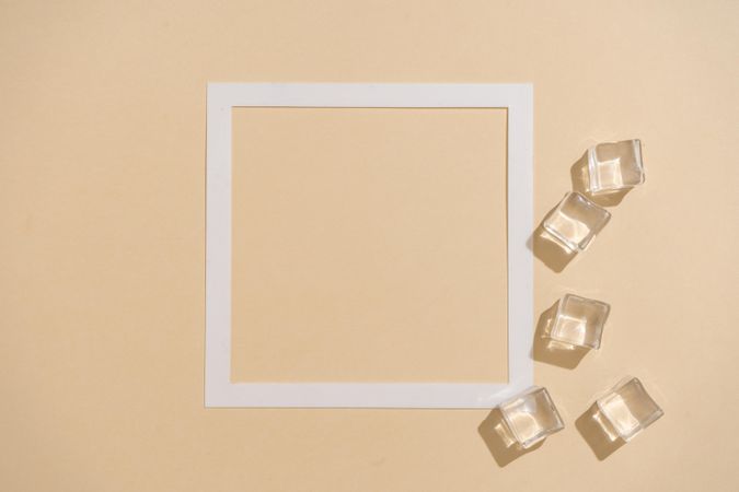 Flat lay of ice cubes on beige background with square