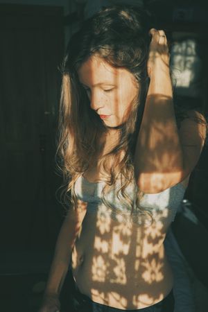 Side view of woman in gray bra looking down and touching her hair