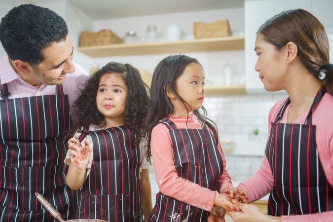 Young girls learning baking from parents in kitchen