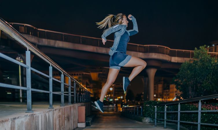 Woman jumping in cardio training exercise in the city at night