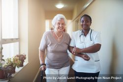 Caring female nurse assisting a older patient to walk 4MqPl4
