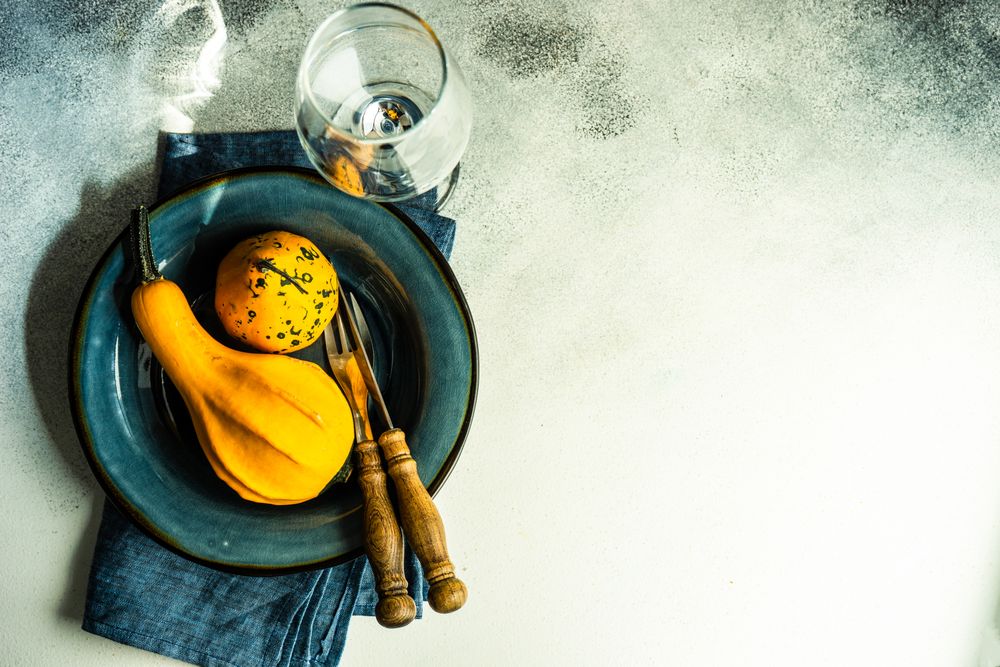 Top view of fall squashes on blue tableware with wineglass, with copy space