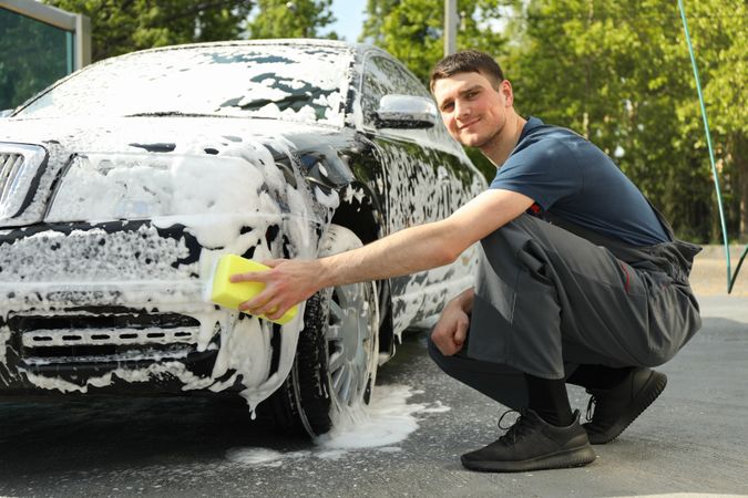 Man wipes the car with a sponge. Car wash. Clear car concept