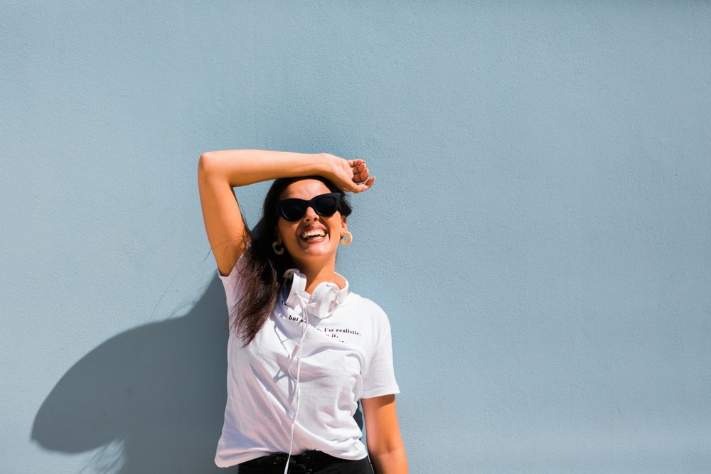 Cheerful casual woman in sunglasses standing on city street