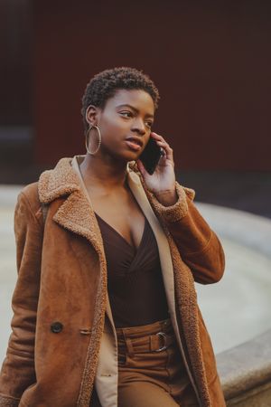Stylish Black woman talking on smartphone on street
