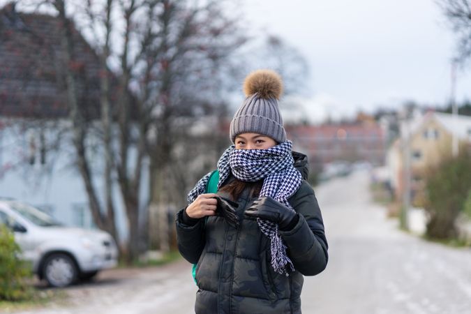 Pleased Asian female tourist in warm clothing at snowy nature