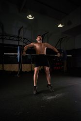Strong sportsman lifting barbell during training in gym