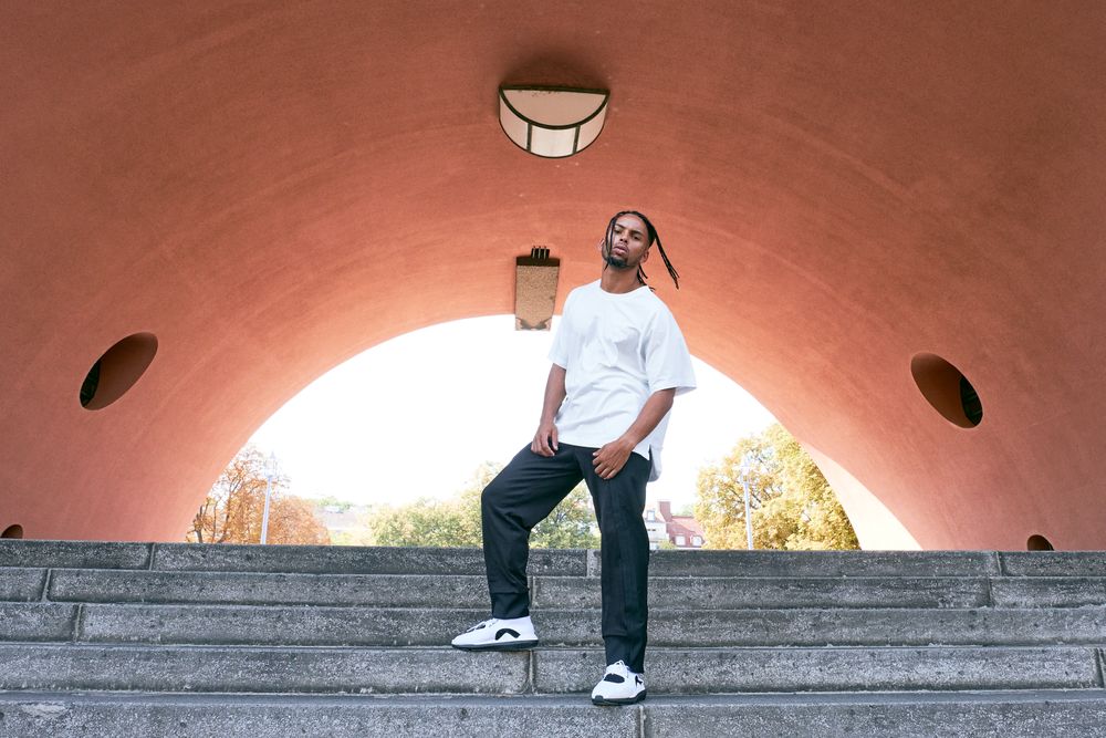 Trendy Black man posing near modern arch