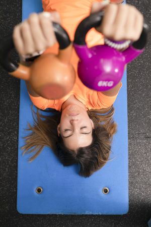 A female trainee lifting a pair of kettlebells during a workout session