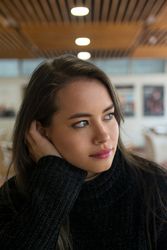 Woman sitting along bookshelves and looking away