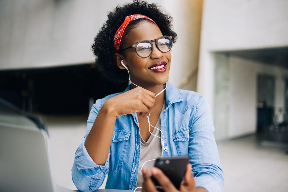 Woman talking on the phone through earbuds in an open office