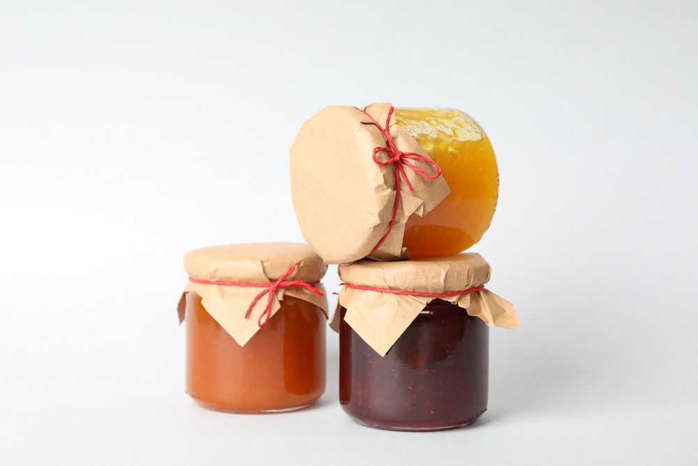 Glass jars with jam on plain background. Sweet food