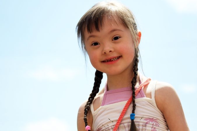 Portrait of a girl with Down syndrome against the sky