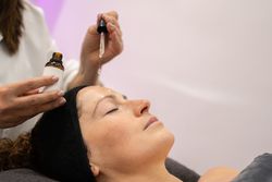 Side view of client with eyes closed having product dripped on forehead