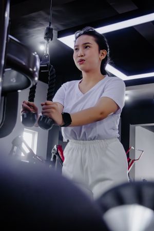 Focused young woman exercising on a machine at the modern fitnes