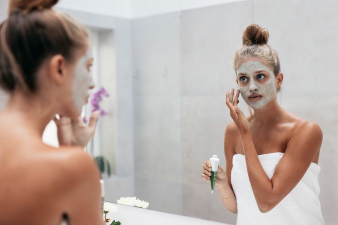 Female with cosmetic mask on face in bathroom