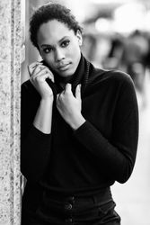 Portrait of serious woman holding neck of her dark sweater outside