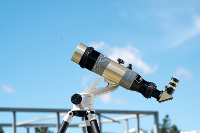 Brass telescope under clear blue sky at observatory.